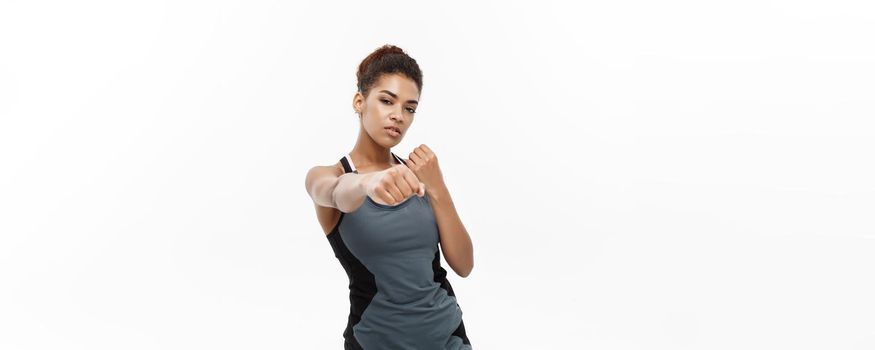 Healthy and Fitness concept - portrait of African American woman punching in air with confident face. Isolated on white background.