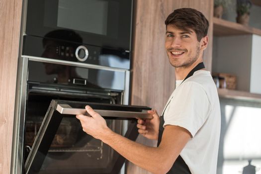 man opening the oven in the home kitchen