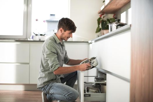 young man looking at clean dishes in dishwasher