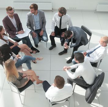team of young employees sitting in a circle in the conference room .