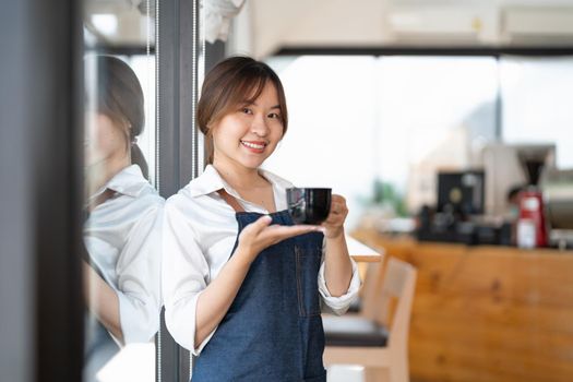 Portrait of woman barista startup successful small Asian business owner in coffee shop.Asian woman barista cafe owner. SME entrepreneur seller business concept.