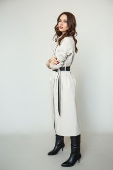 The girl is a model in a coat dress with a leather belt. Studio background. Advertising clothes for the showroom