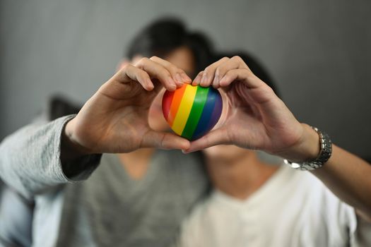 Rainbow heart shape in homosexual couple hands. LGBT, pride, relationships and equality concept