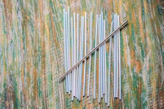 Steel drinking vs disposable straws on painted wooden background. Zero waste concept