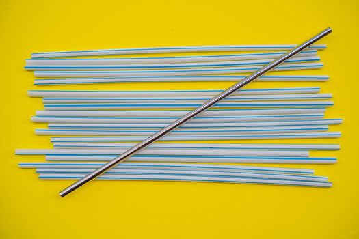 Steel drinking vs disposable straws on a yellow background. Zero waste concept