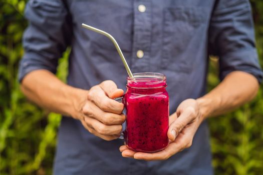 Dragon fruit smoothie with steel drinking straw in male hands