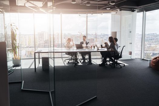 Team of businessmen communicating together in modern office with panoramic windows