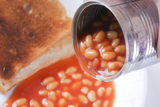 Tasty baked beans pouring from a can container