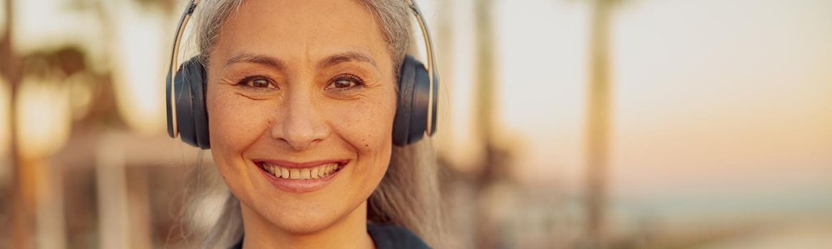 Portrait of happy woman listening to music on headphones on the beach