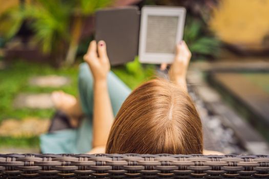 Woman reads e-book on deck chair in the garden