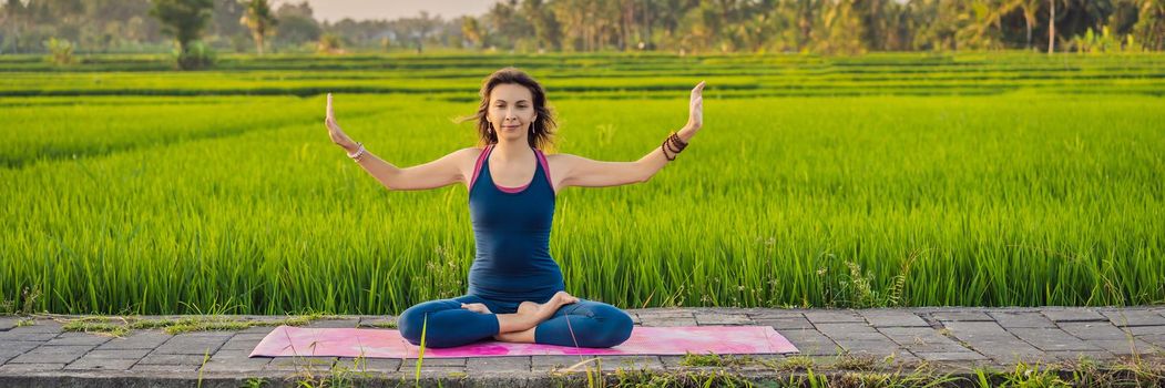Young woman practice yoga outdoor in rice fields in the morning during wellness retreat in Bali BANNER, LONG FORMAT