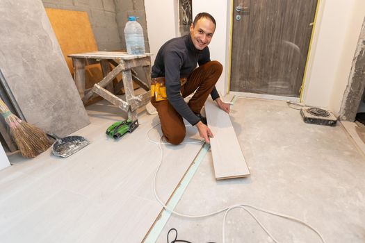 carpenter worker installing laminate flooring in the room.