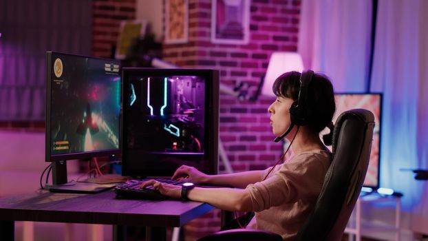 Caucasian gamer girl relaxing playing fast paced space shooter simulation on professional pc setup
