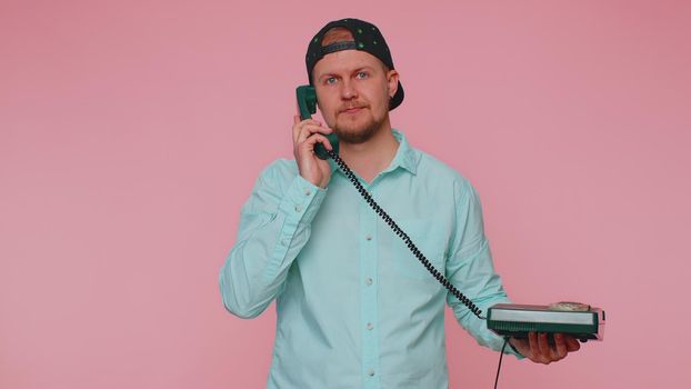 Cheerful tourist man secretary talking on wired vintage telephone of 80s, says hey you call me back