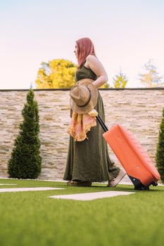young woman traveller, entering hotel reception with her wheeled suitcase. woman on recreational trip. concept of rest and holiday.