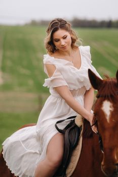 A woman in a white sundress riding a horse in a field