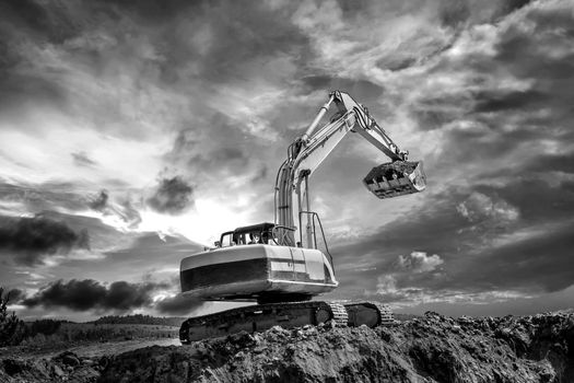 Crawler excavator during earthmoving works on construction site in black and white