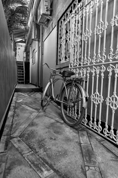 Old bicycle in black and white. Bike left at the fence on the street
