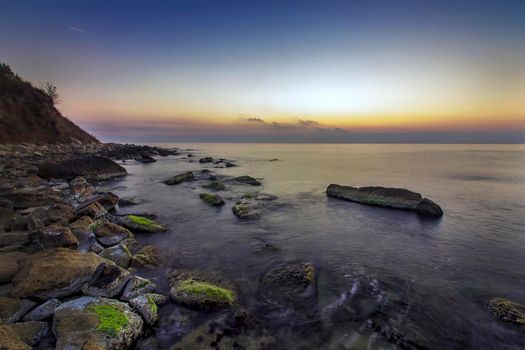 Relaxing long exposure seascape of rocky coast before sunrise.