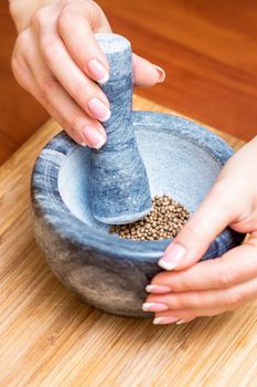 Hands of woman grinding pepper in mortar