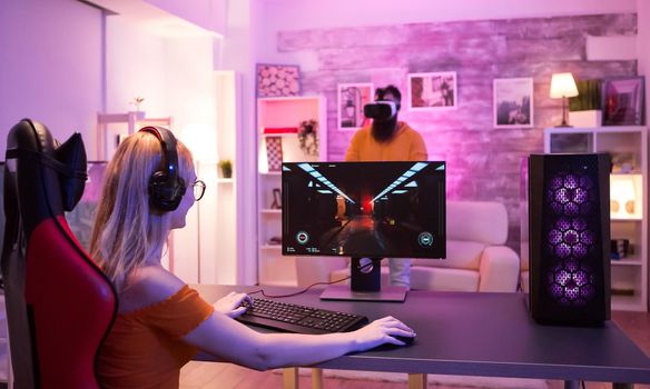 Blonde girl sitting on gaming chair in a room with colorful neon light