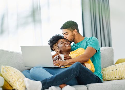 Portrait of a lovely young couple together holding laptop on sofa at home