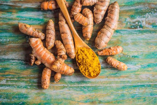 Turmeric root and turmeric powder on color wooden background