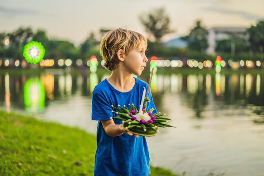 Boy tourist holds the Loy Krathong in her hands and is about to launch it into the water. Loy Krathong festival, People buy flowers and candle to light and float on water to celebrate the Loy Krathong festival in Thailand