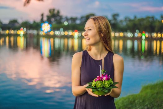 A female tourist holds the Loy Krathong in her hands and is about to launch it into the water. Loy Krathong festival, People buy flowers and candle to light and float on water to celebrate the Loy Krathong festival in Thailand