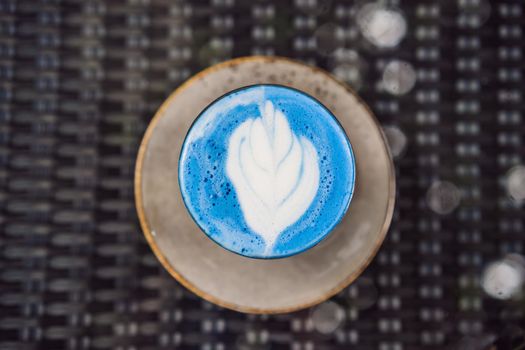 Trendy drink: Blue latte. Top view of hot butterfly pea latte or blue spirulina latte on gray textured background. Copy space for text
