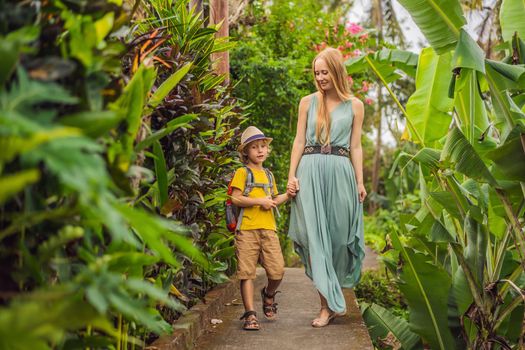Mother and son tourists in Bali walks along the narrow cozy streets of Ubud. Bali is a popular tourist destination. Travel to Bali concept. Traveling with children concept