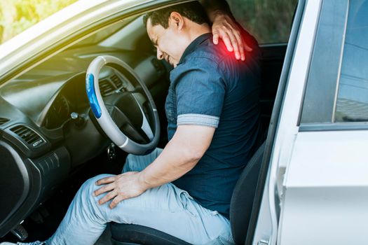 A car driver with muscle pain, concept of a man in his car with neck pain. An exhausted driver with back pain, A person with muscle pain in traffic