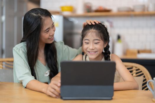 Happy mother with her young daughter enjoying in online shopping or working from home. Business from distance and virtual communication with family and friends