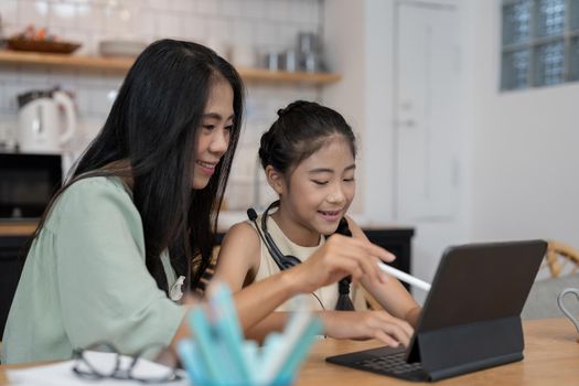 Asian young mother with computer notebook teaching kid to learn or study online at home, Homeschooling online concept