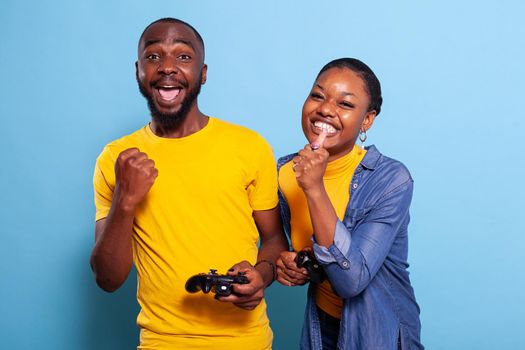 Joyful couple winning video games with joystick on console