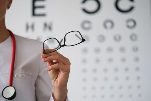 Woman doctor ophthalmologist shows glasses, close-up, blurry