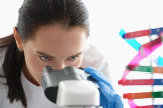Woman scientist looking through a microscope, studying dna