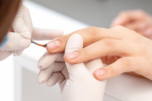Hand of manicurist applying clear nail polish