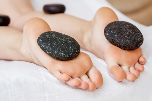 Hot stones lying on female feet