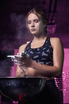 Female fitness model clapping hands with talc powder in a gym just before doing exercise.