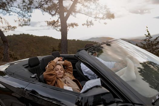 Smiling beautiful female relaxed in convertible car traveling with man, honeymoon concept