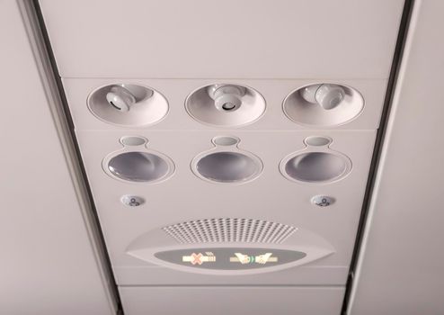 Adjustable lights and air conditioners overhead seat controls of a commercial aircraft in an airplane with no-smoking and seat belt on signs