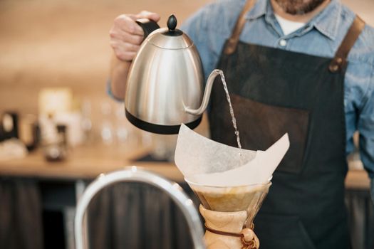 Close up of man barista making filter coffee in cafeteria