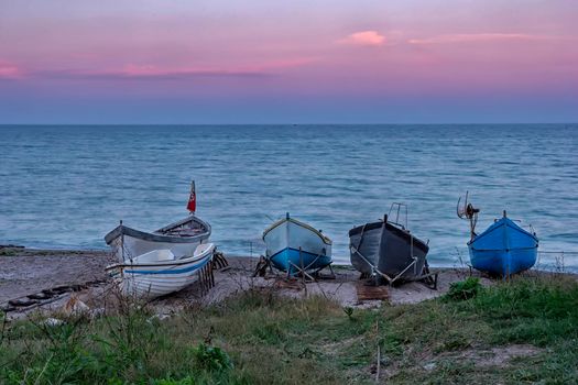 several wooden boats on the sand after sunset