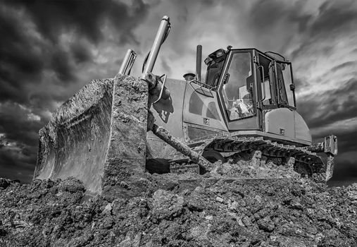 Amazing black and white view of stopped bulldozer and blade into the ground. Wide angle, close up
