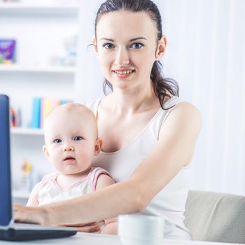 young mother and baby using laptop to communicate with grandma via skype