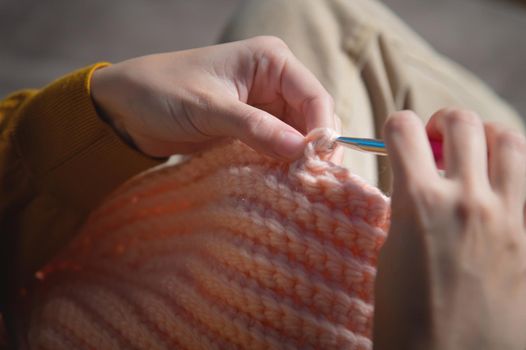 female hands close-up, crocheting clothes on the sofa at home, handmade