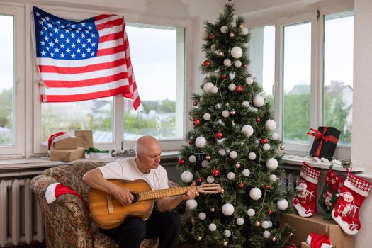 Man playing acoustic guitar, American flag, at christmas