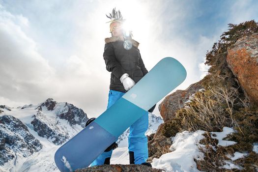 Beautiful young woman in mohawk hat holding a snowboard in front of her
