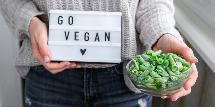 Lightbox with text GO VEGAN in female hands. Veganism, vegetarian healthy lifestyle. Frozen food in bowl. Green beans